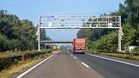 LKW fährt auf der A57 unter einer Mautbrücke durch