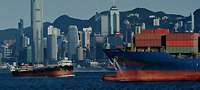 Blick auf den Hafen in Hongkong mit Containerschiff im Vordergrund