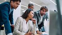 Concerned businessmen and -women look into a computer screen