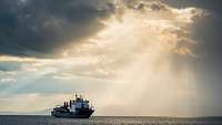 Merchant ship at sea with beam of light 