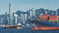 Blick auf den Hafen in Hongkong mit Containerschiff im Vordergrund