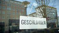 Schild mir Aufschrift "Geschlossen" an einer Fensterscheibe