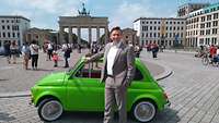 Torsten Wunderlich steht vor einem grünen Fiat vor dem Brandenburger Tor in Berlin