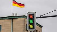 Ampel vor einem Gebäude zeigt gleichzeigit rot, grün und gelb